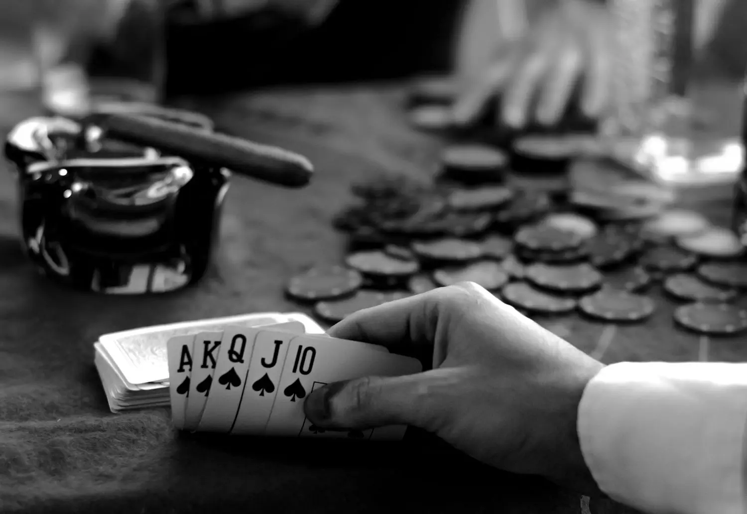 Close-up of a card hand and chips in monochrome cinematic light